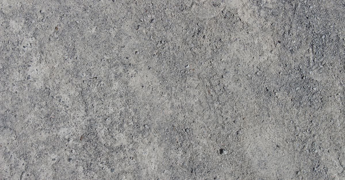 Worker preparing a concrete wall by cleaning dust and loose particles before applying silicone primer.